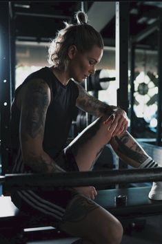 a woman sitting on top of a bench in a gym