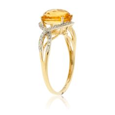 a yellow and white gold ring with an oval cut citrine surrounded by diamonds