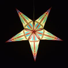 an origami star hanging from a string in the dark with lights on it