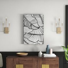 a black and white painting hangs on the wall above a wooden cabinet in a living room