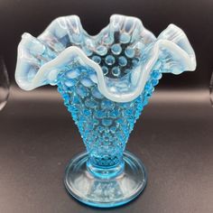 a blue glass vase sitting on top of a table