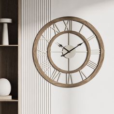 a wall clock with roman numerals is on the wall next to a bookshelf