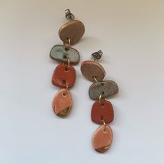 three pairs of earrings with different shapes and colors on them, hanging from gold earwires