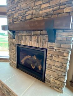 a stone fireplace in a living room next to a window