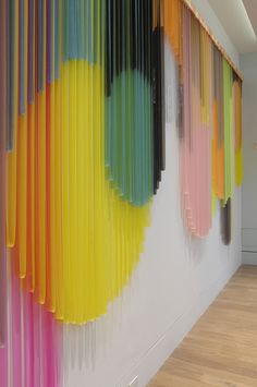 the wall is covered with colorful curtains in an art gallery