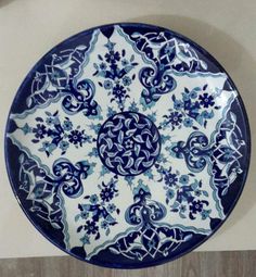 a blue and white plate sitting on top of a wooden table next to a wall