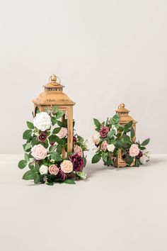 two small wooden lanterns with flowers on them