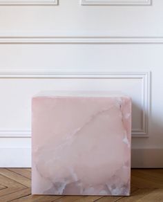 a pink marble block sitting on top of a wooden floor next to two framed pictures