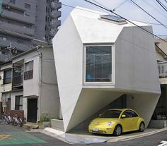 a yellow car is parked in front of a white building on the corner of a street