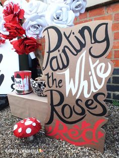 a sign that says dying the white roses next to some red and white paper flowers