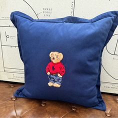 a blue pillow with a teddy bear embroidered on it