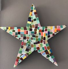 a multicolored mosaic tile star hanging on a gray wall in front of a door