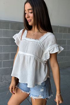 Dreamy top alert! This flowy piece is made from lightweight fabric that feels amazing against your skin. It's oversized for a comfy fit, but the ruffled sleeves and peplum hem add a touch of sweetness. Raw edge details keep it trendy, making it perfect for anything from picnics to brunch! Square neckline Short ruffled sleeves Raw edge seam details Peplum hem Lightweight gauzy fabric Oversized fit 100% Cotton Fit and sizing: Measurements are approximate. Length measurements are taken from the top Cute Oversized Shirt Outfits, Cute Modest Tops, Summer Outfits Flowy, Ruffle Top Outfit, Flowy Tops Outfit, Trendy Brunch Outfit, Ingenue Natural, Mass Outfit, Brunch Fits