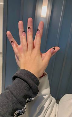 a woman's hand with black and white nail designs on it, in front of a blue wall