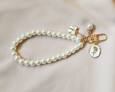 Vintage pearl keychain charms. These are highly durable and perfect to accessorize your purse, airpods or keys.  Circumference measures 8.5 inches. Please ensure that you are not stretching the keychains as they will wear out overtime or break. These do not stretch. If you would like a certain sizing please contact us.1 Gold Rectangular Wristlet For Gifts, Elegant Adjustable Wristlet For Gift, Elegant Keychain With Key Leash As Gift, White Keychain With Lobster Clasp For Gift, White Keychain With Lobster Clasp As Gift, White Wristlet With Keychain As Gift, Elegant Gold Wristlet As Gift, White Rectangular Keychains For Gifts, Rectangular Wristlet With Key Leash As Gift