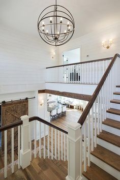 an open floor plan with wood floors and white railings, along with a chandelier that hangs from the ceiling