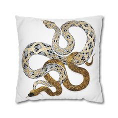 a white pillow with a yellow and black snake design on it's front side