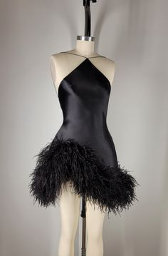 Fin  Black silk sueded satin backless halter, tapered neckline suspended by dainty satin cord. Asymmetrical hem embroidered with custom dyed pure ostrich feathers. Invisible zipper at center back.    Color and length may be customized. May be paired with custom designed sleeves and gloves. FAQS HOW LONG DOES THE PROCESS TAKE? Each look is custom made to order with precise measurements. Ideally requiring a minimum of 8 weeks.  If faster delivery is needed, a priority reservation can be placed with this listing: https://www.etsy.com/listing/1606891070/priority-reservation WHAT MEASUREMENTS ARE REQUIRED?  Your unique measurements are the most important part of the process. These measurements will be needed to begin work on your garment. * BUST (Around the fullest part of the chest, including Formal Mini Dress Outfit, Black Sequin Cocktail Dress, Waist Drop Dress, Satin Birthday Outfit, Black Salsa Dress, Edgy Cocktail Attire, Custom Made Birthday Dress Black Women, Asymmetrical Mini Dress, Ostrich Feather Outfit