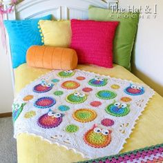 a crocheted blanket on top of a bed next to pillows