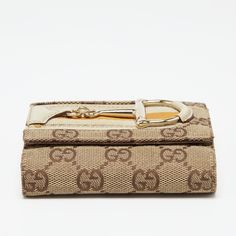 Gucci Beige GG Canvas and Leather Web Horsebit Compact WalletThis Gucci wallet is stacked with signature details. Created from the GG canvas and leather it is adorned with a Horsebit on the front and exhibits gold tone hardware. The compartmentalized interior of this wallet will keep your monetary essentials organized. Size: Height: 9 cm Width: 2.5 cm Length: 11 cmColour: BeigeMaterial: Canvas Leather Compact Wallet, Gucci Wallet, Gold Ounce, Wallet Fashion, Fendi Bags, Canvas Leather, Prada Bag, Dior Bag, Chanel Bag