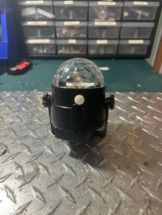 a black object sitting on top of a metal table next to some drawers and bins