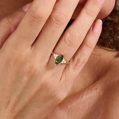 a woman's hand with a ring on her finger and an emerald stone in the middle