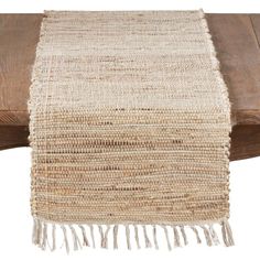 a close up of a wooden bench with a woven table runner on top of it