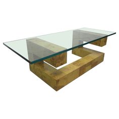 a glass and wood coffee table with two wooden bases on one side, the other end is