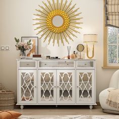 a living room with white furniture and a gold sun mirror