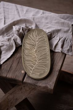 a wooden table topped with a metal plate covered in leaf design on top of it