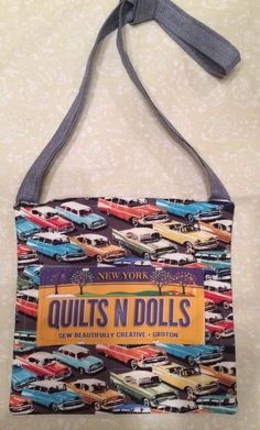 a bag that has cars on it and the words quilts n dolls printed on it