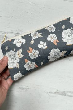 a hand holding a black and white flowered pencil case