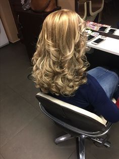 a woman is sitting in an office chair with her back turned to the camera and she has long blonde hair