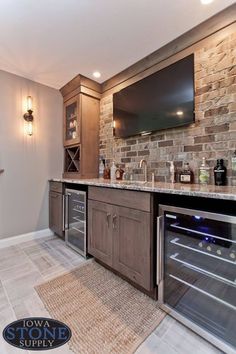 a kitchen with stone walls and stainless steel appliances in the center, along with built - in wine coolers