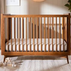 a wooden crib in the corner of a room with white walls and flooring