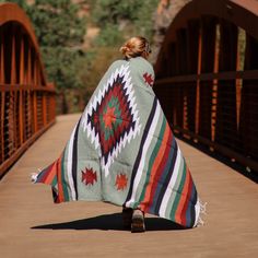 a woman walking across a bridge holding a blanket