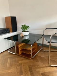 a glass table with two chairs next to it and a potted plant on top