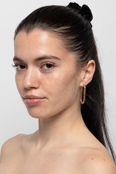 a woman with freckled hair wearing large gold hoop earrings on her left ear