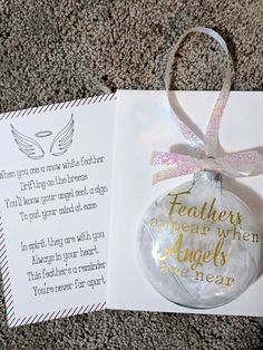 an ornament with a message on it sitting next to a card that says, feathers appear when angels are near