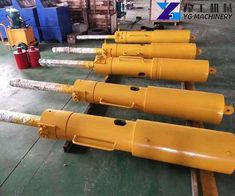 four yellow cylinders sitting on top of a floor next to other equipment in a warehouse