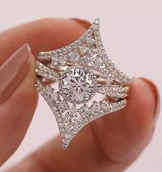 a woman's hand holding a diamond ring in front of her face, with the center stone surrounded by smaller diamonds