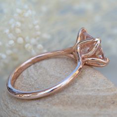 a pink diamond ring sitting on top of a rock