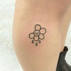 a woman's leg with a small tattoo of a flower and raindrops