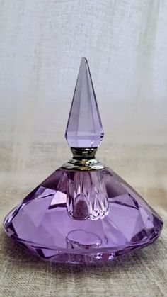 a purple perfume bottle sitting on top of a table