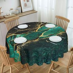 a dining room table covered with a green and gold marbled tablecloth that has white plates on it