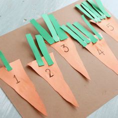 paper cut out to look like carrots on a piece of brown paper with numbers