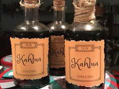 two bottles of kahlua sit on a table next to each other with twine