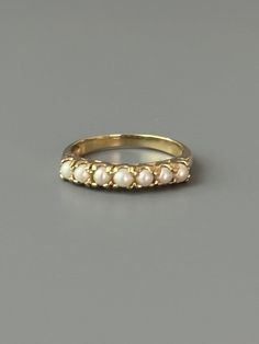 Size: 6.5US Weight: 1.9g Dimensions: 1/8" tall Hallmarks: 10K This sweet little pearl ring is in the style of a half eternity ring and hails from the mid century.  Seven luscious and lucky whole pearls nestle inside 10k yellow gold. This ring makes a great stacking ring with gold bands and other gold gemstone rings. Excellent condition.  Patina as found Expanded shop policies under FAQ Classic Stackable Pearl Ring, Classic Stackable Pearl Ring For Formal Occasions, Formal Stackable Pearl Ring Fine Jewelry, Formal Stackable Pearl Ring, Fine Jewelry, Stackable Pearl Ring For Formal Events, Stackable Pearl Ring For Formal Occasions, Classic 14k Gold Stackable Pearl Ring, Vintage Half Eternity Jewelry As A Gift, Vintage Stackable Rings For Formal Occasions