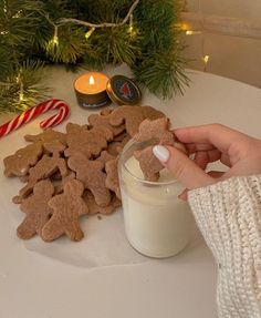 a person is holding a cookie in front of some cookies on a table next to a candle