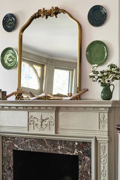 a fireplace with plates on the mantle and a mirror above it